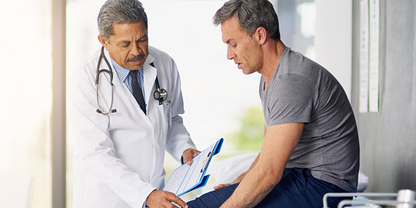 physician speaking with male patient about leg pain